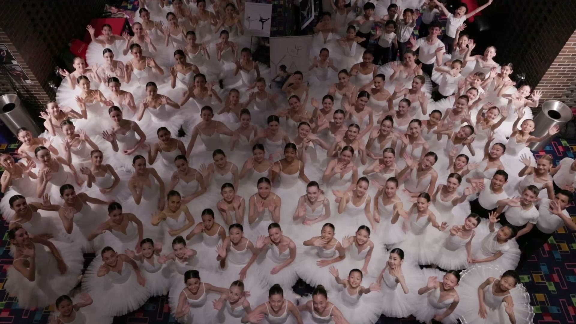Aerial view of a large group of ballet students in white gathered together